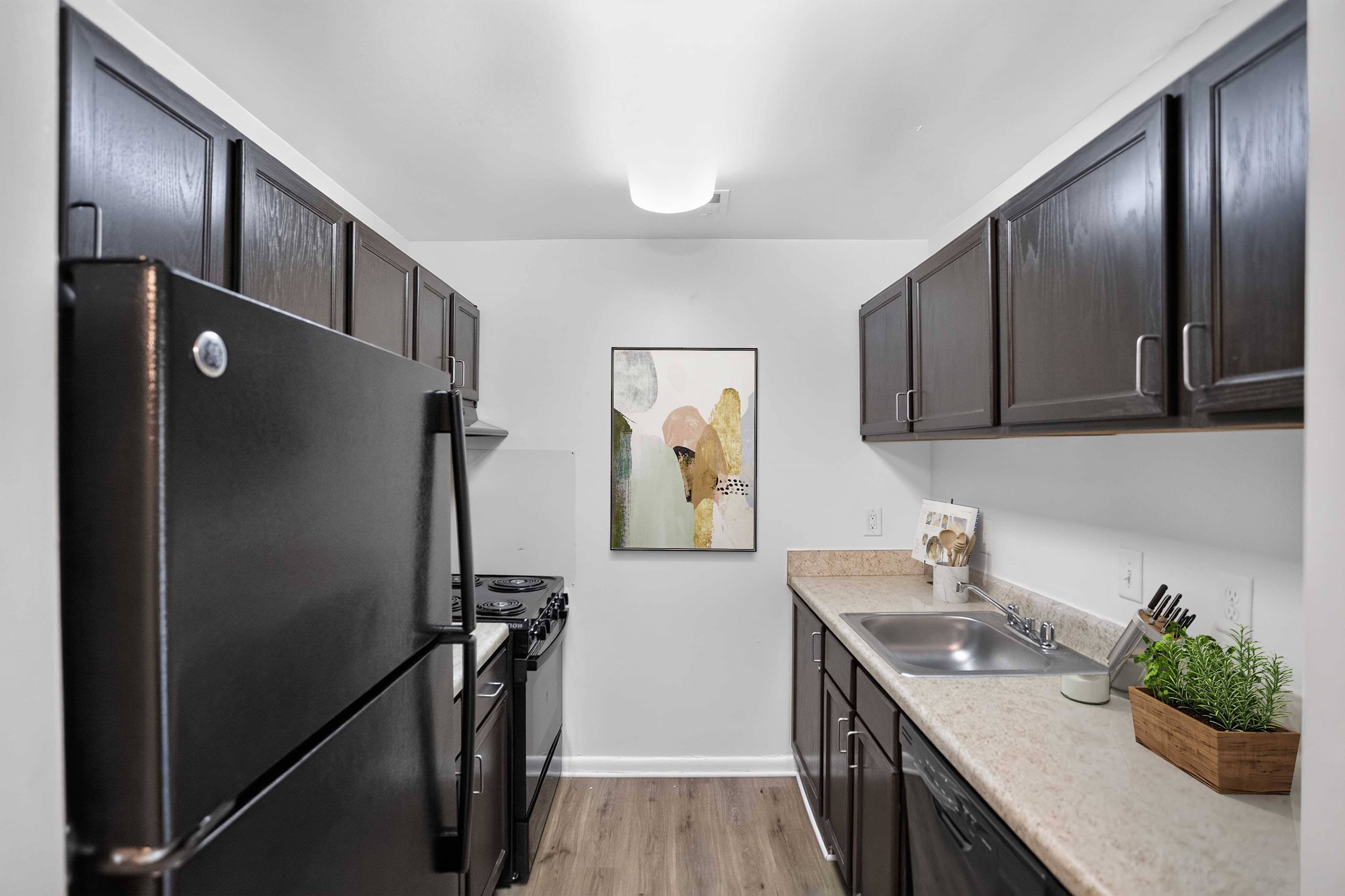 A kitchen with black cabinets and a fridge.